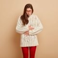 A woman keeps her hands on her stomach due to cramps